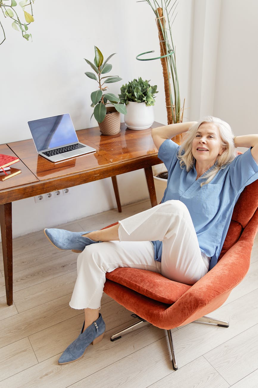 woman in blue long sleeve shirt and white pants sitting on an armchair
